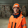 Nicklas Johansson, site manager in Finland, standing in a recycling facility with hi-vis protective gear. In the background recycled paper.