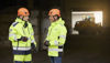 Two male Stena Metall Group employees in hi-vis protective gear have a discussion in a Stena facility. 