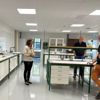 En kvinna och två män står runt ett bord i en laboratoriemiljö