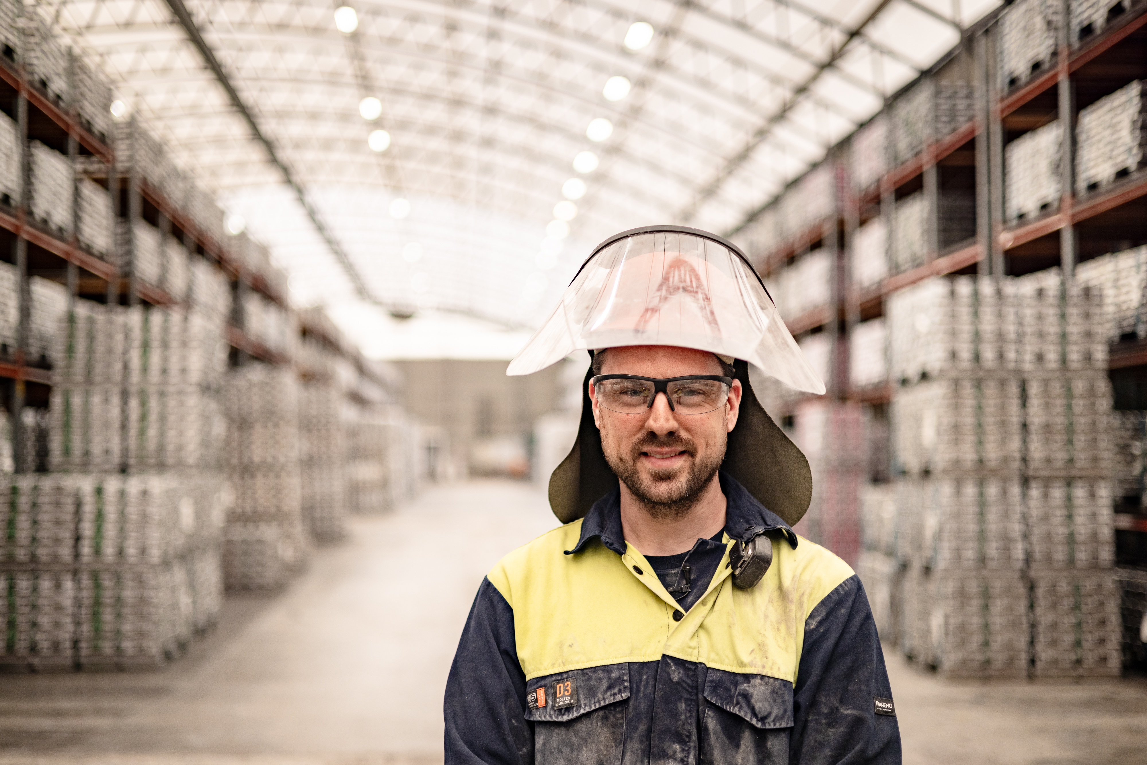 Oskar Rundberg, operator at Stena Aluiminium’s smelter, dressed in hi-vis protective gear, standing in the facility where aluminium ingots are stored.