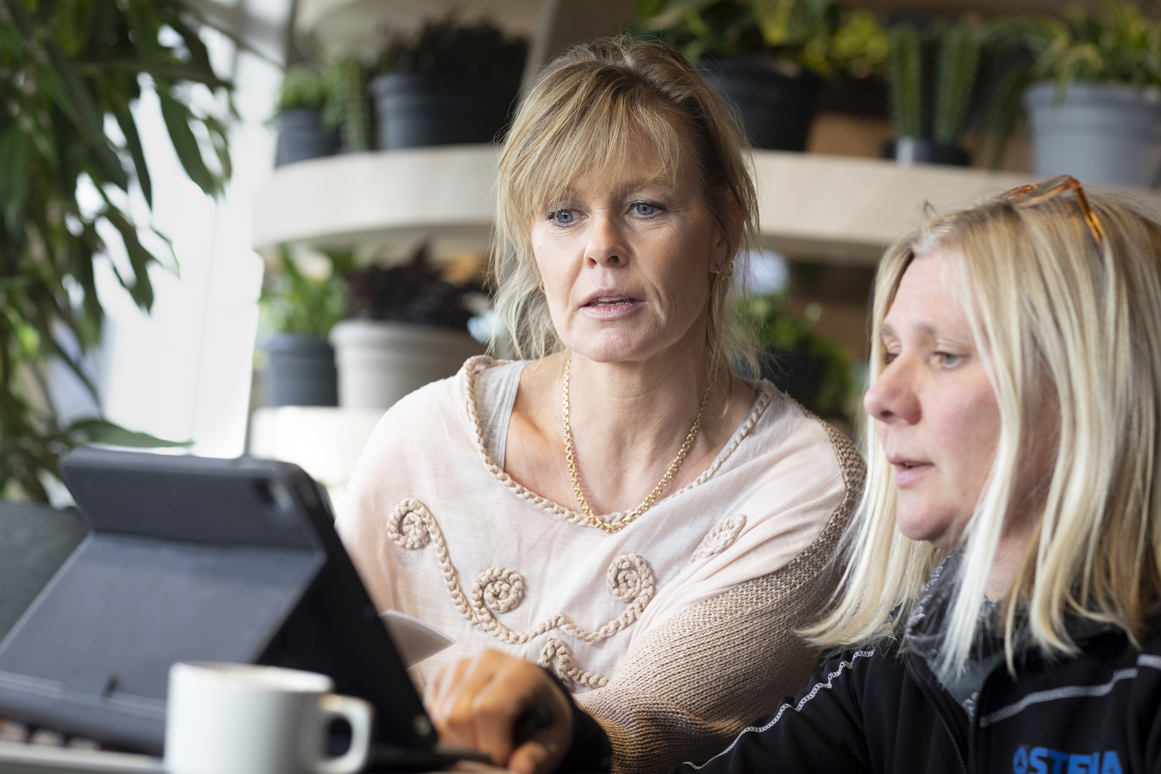 Två av Stena Metallkoncernens medarbetare har en laptopdiskussion med anläggningar i bakgrunden.