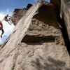 Two climbers scale a rock face – one holds the other in mid-air by the hand.