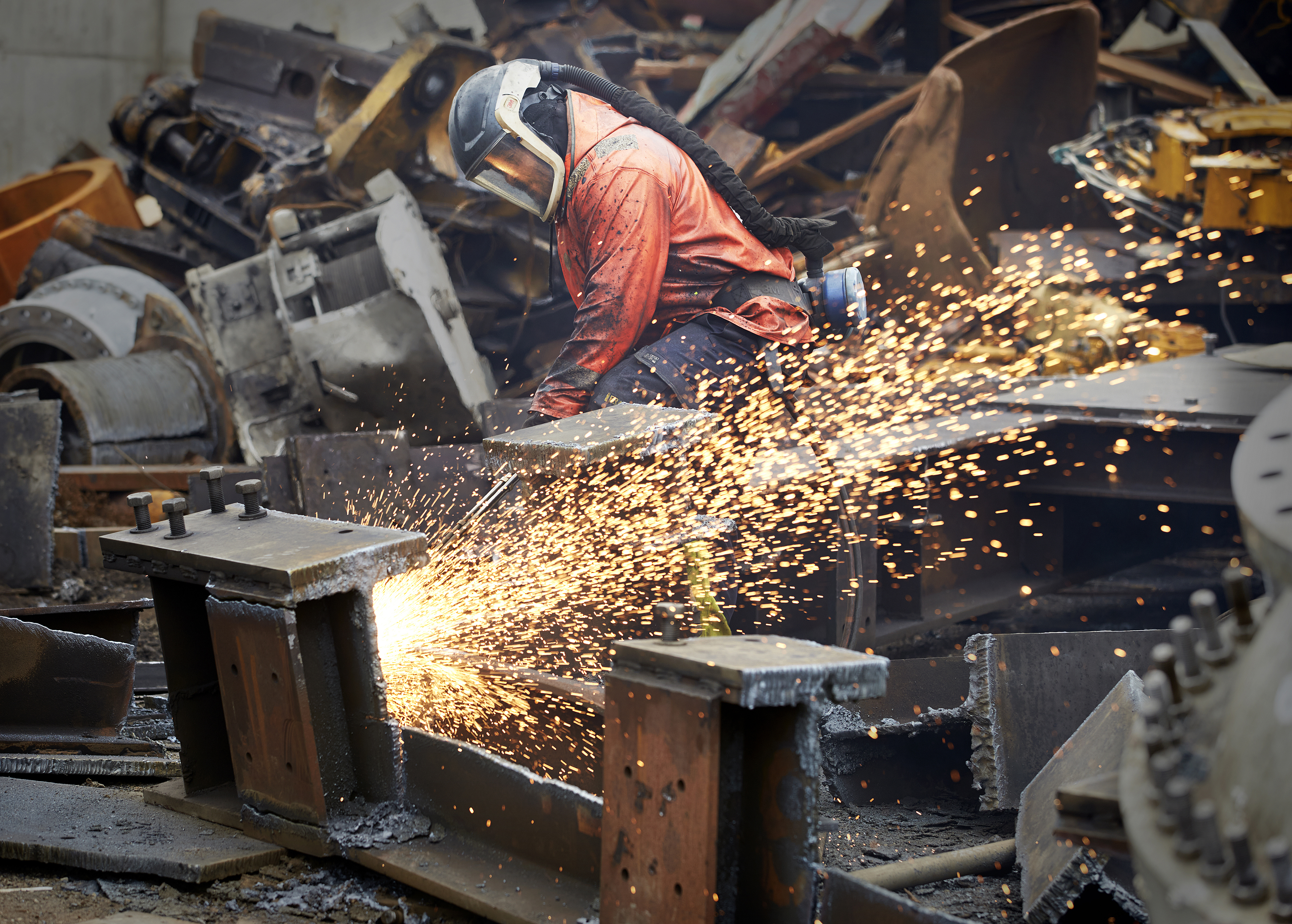 A Stena Metall Group employee wearing protective gear cuts metal in a Stena facility.