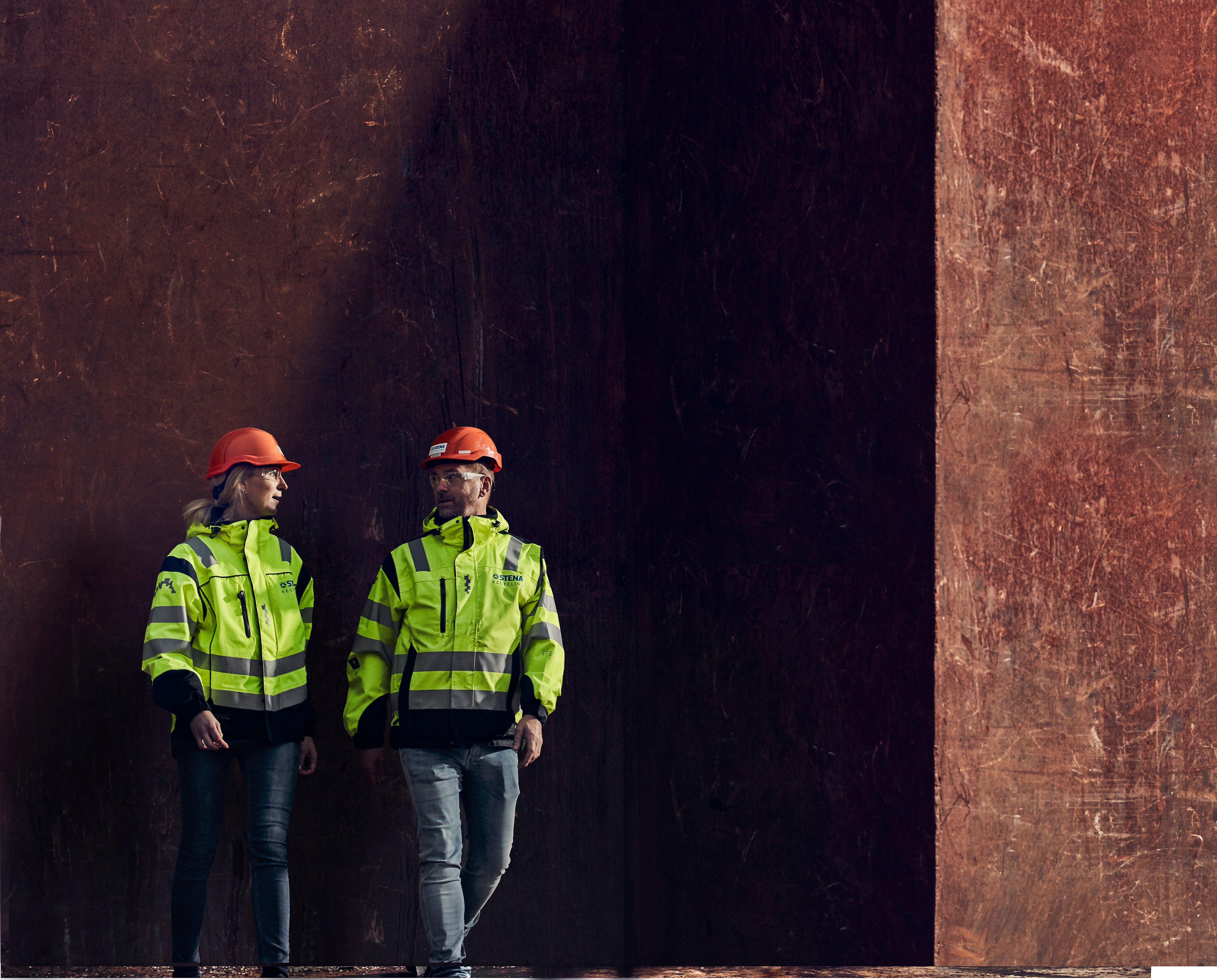 Två av Stena Metallkoncernens medarbetare – en man och en kvinna  i varselkläder – pratar tillsammans.