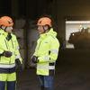 Two male Stena Metall Group employees in hi-vis protective gear have a discussion in a Stena facility.