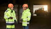 Two male Stena Metall Group employees in hi-vis protective gear have a discussion in a Stena facility. 