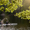 Two people paddle in a canoe on a Swedish lake as the sun shines.