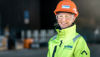Kvinnlig expert från Stena Metall Group som tittar in i kameran, klädd i reflekterande arbetsjacka och hjälm med Stena Recyclings logotyp