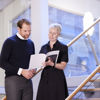 Two Stena Metall Group employees stand on a staircase and look at a document together.