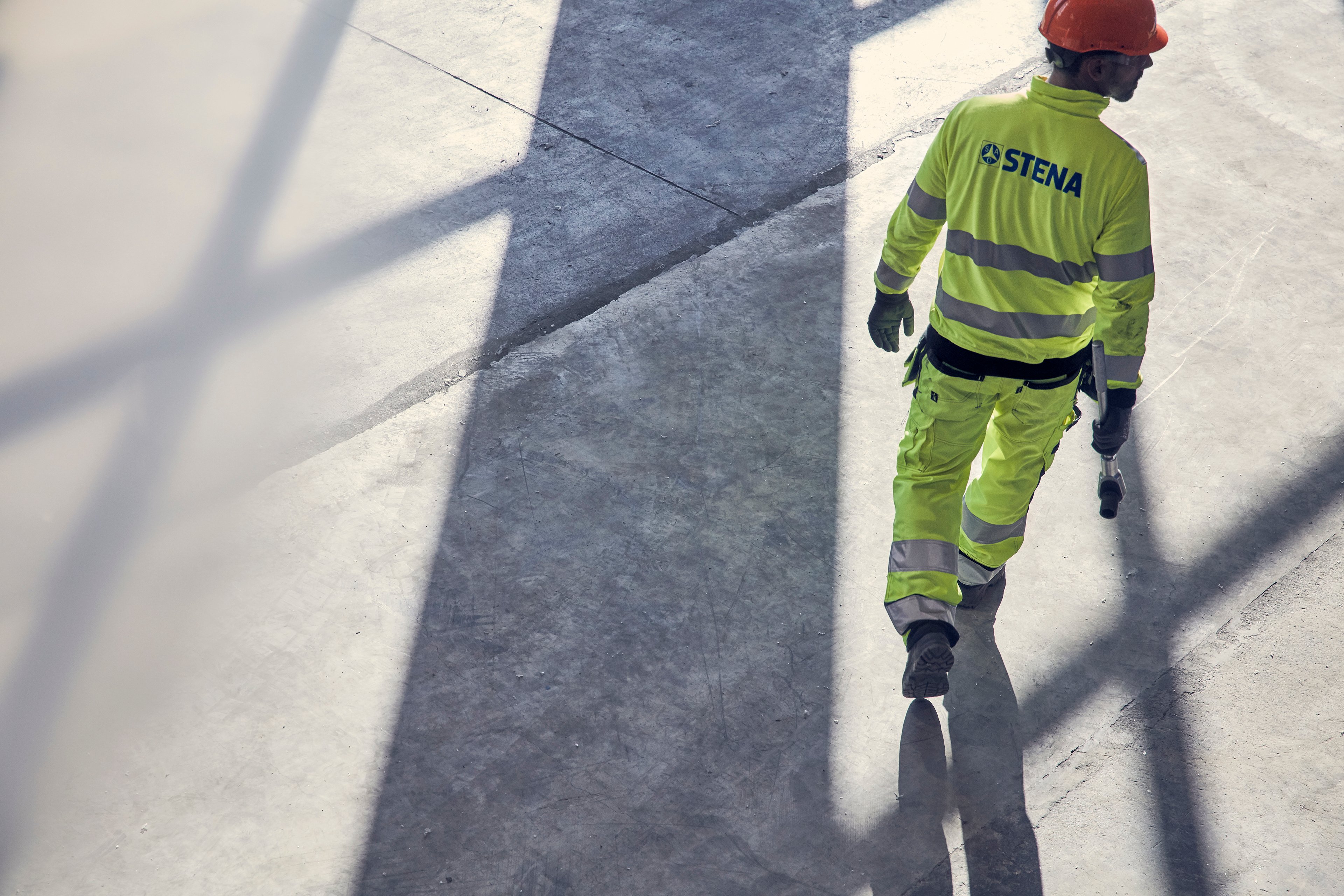 A rear shot of a Stena Metall Group employe wearing hi-vis gear and a protective hard hat.
