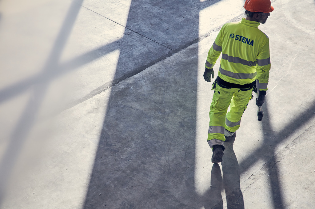 The back of a male Stena Metall employee in hi-vis protective gear and helmet.
