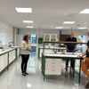 A woman and two men are standing around a table in a lab environment