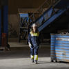 A Stena Metall Group employee wearing protective gear walks past a recycling container in a Stena facility.