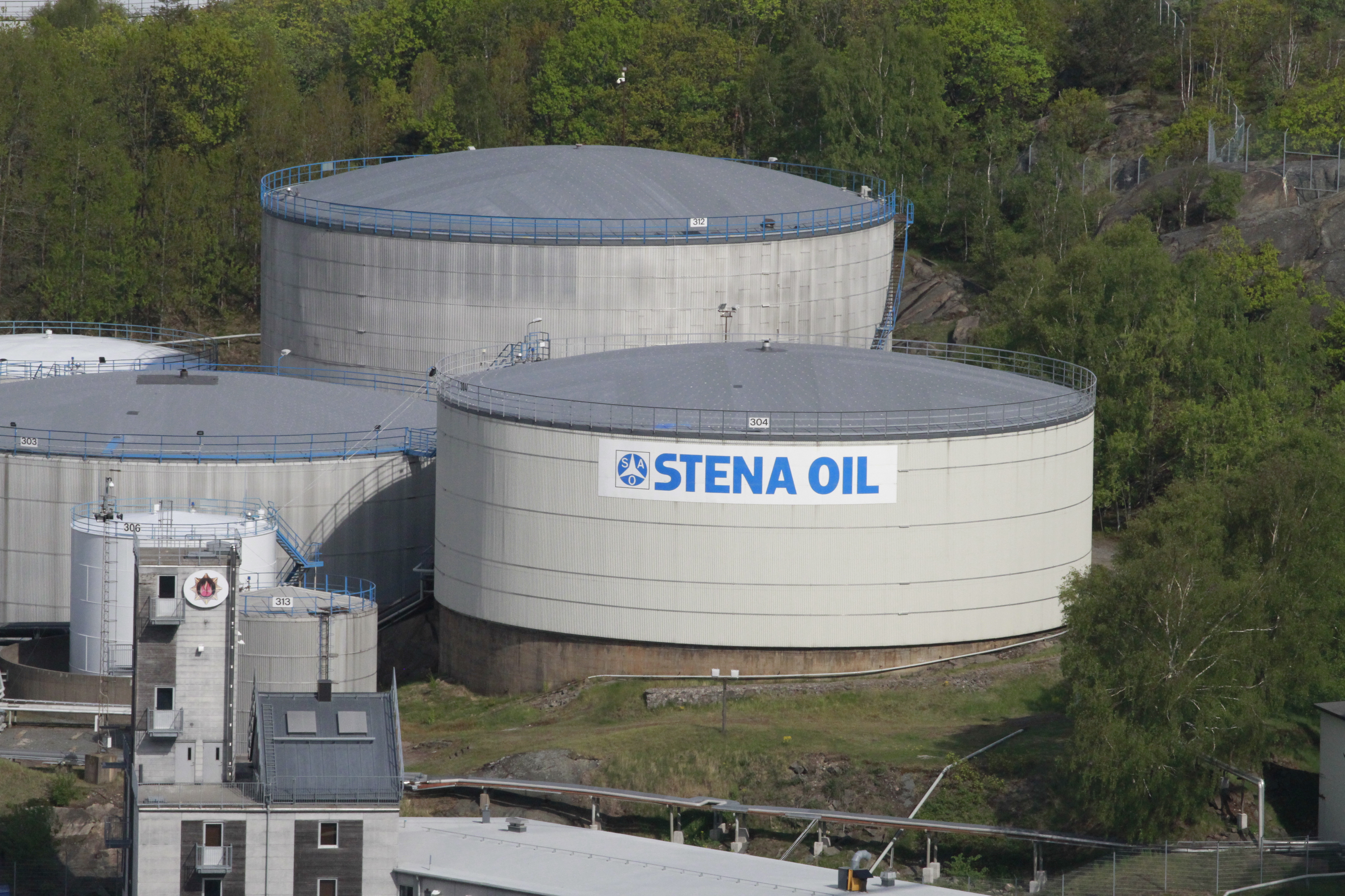 Three white Stena Oil facilities surrounded by green trees.