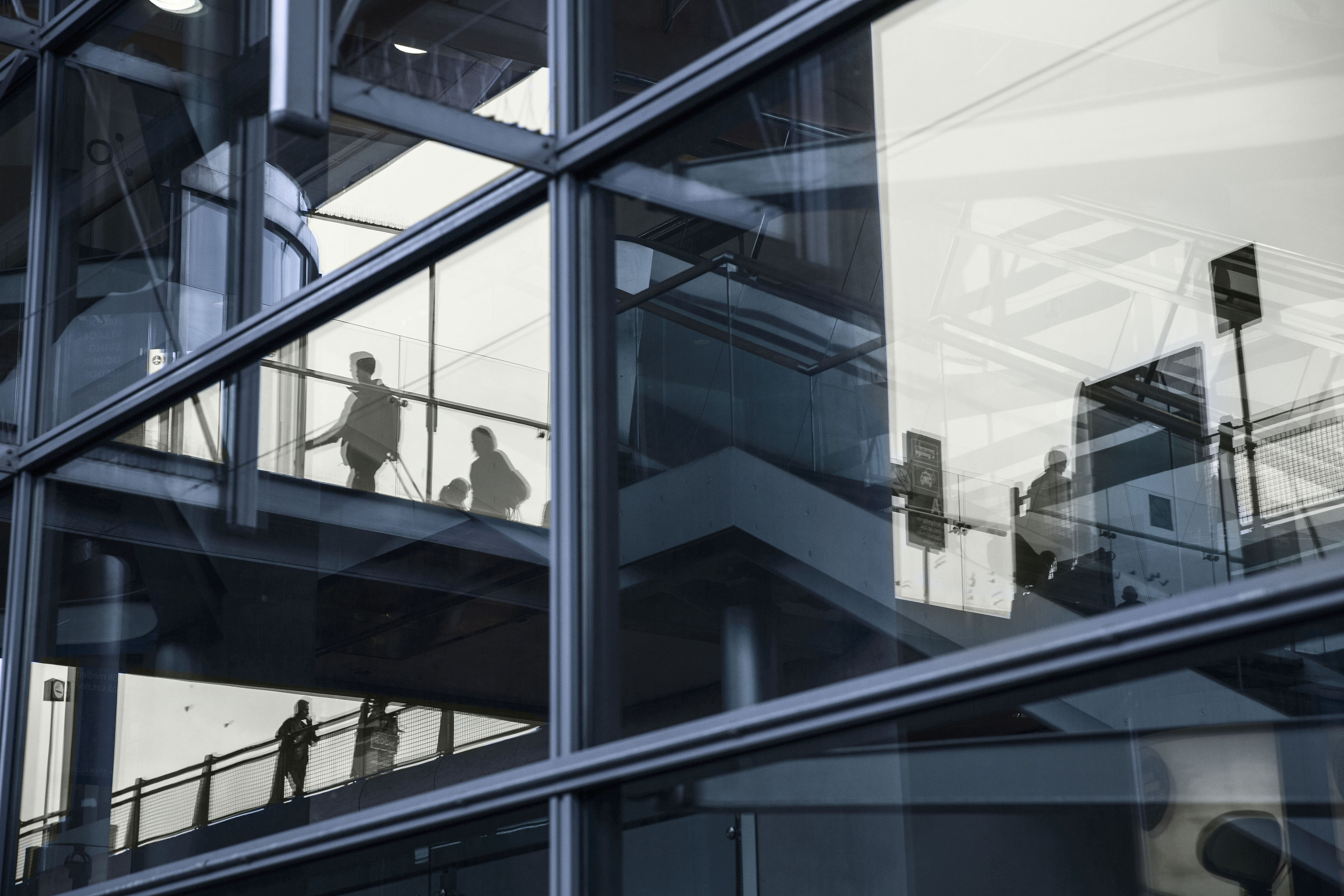 Figures reflected in the glass exterior of a modern office building.